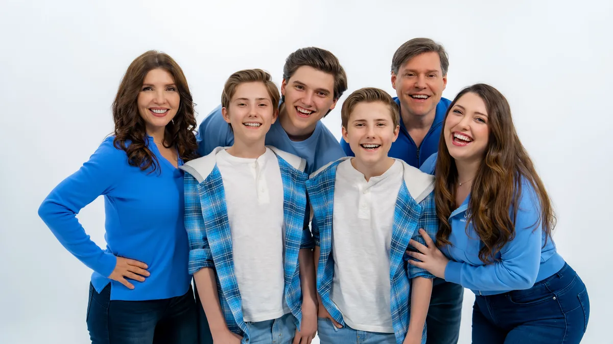 The six Sharpe Family Singers laughing together in a white studio